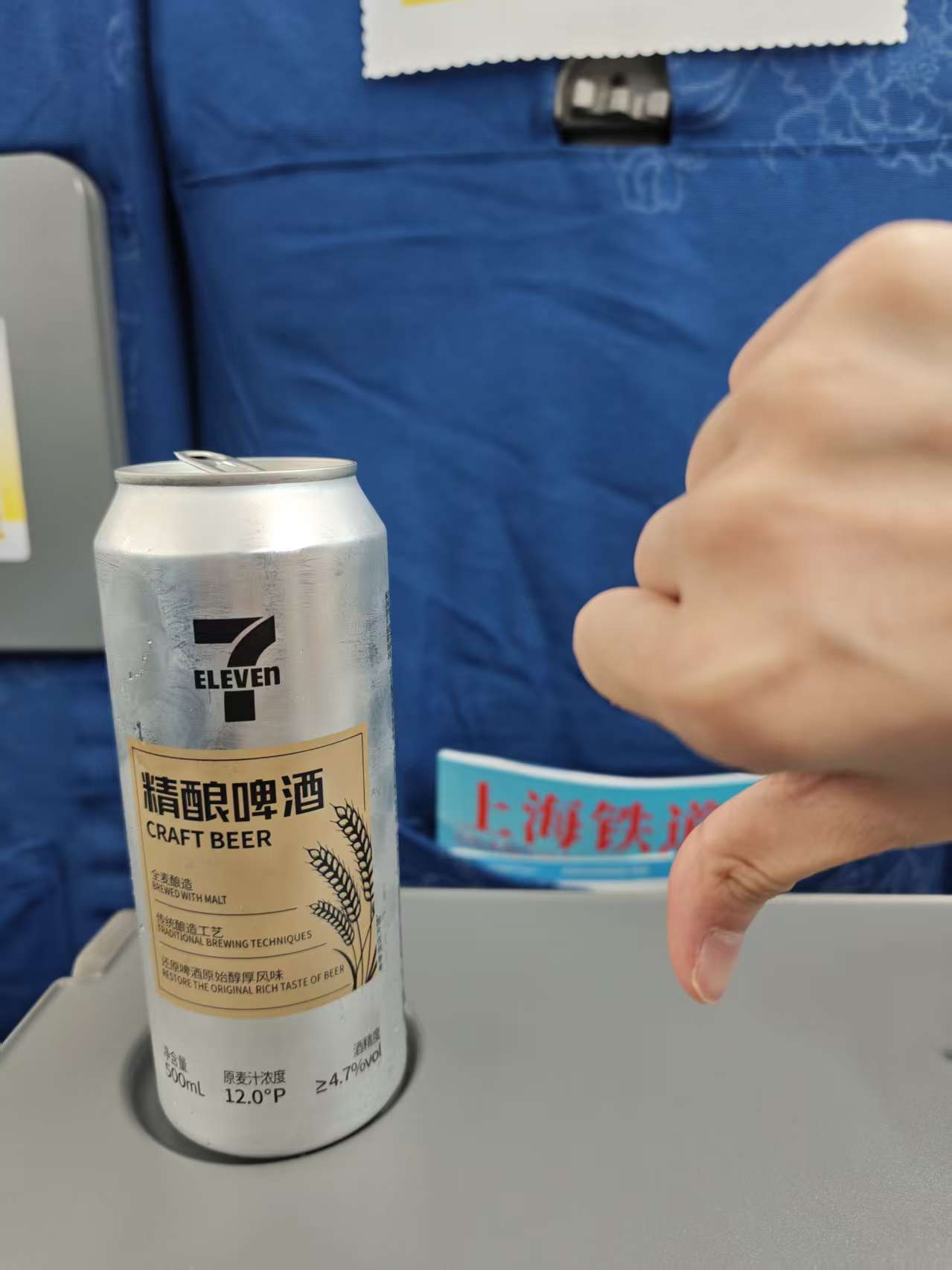 列车座位前的啤酒和倒过来的拇指